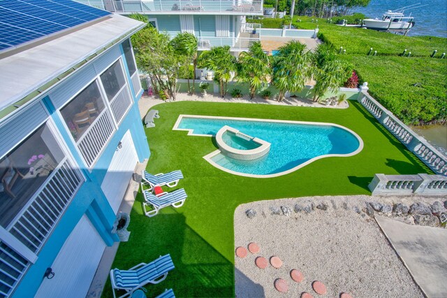 view of pool featuring an in ground hot tub, a water view, and a lawn