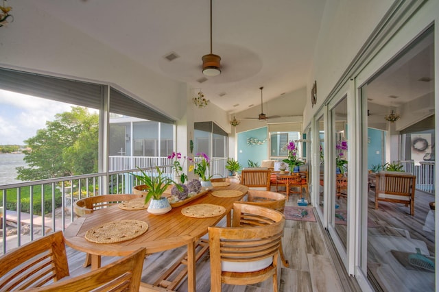 sunroom / solarium with lofted ceiling, ceiling fan, and a water view