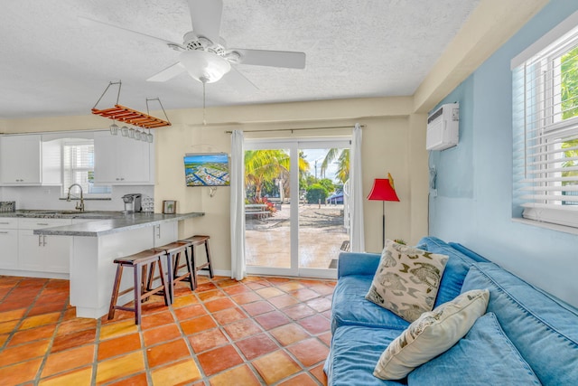 living area with ceiling fan, a textured ceiling, light tile patterned floors, and a wall mounted AC