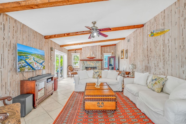 living room with beam ceiling, wood walls, light tile patterned floors, and ceiling fan