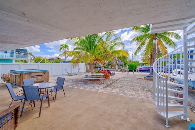 view of patio featuring a hot tub, fence, and stairway
