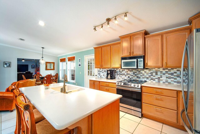 kitchen with an island with sink, appliances with stainless steel finishes, sink, and pendant lighting