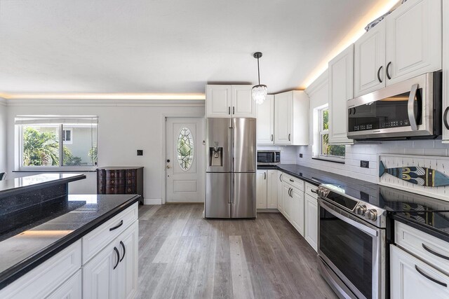 kitchen featuring stainless steel appliances, white cabinetry, and hanging light fixtures