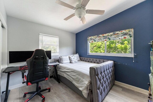 bedroom with multiple windows, lofted ceiling, ceiling fan, and light wood-type flooring