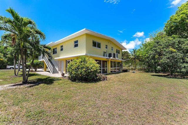 back of property with cooling unit, a yard, and a sunroom