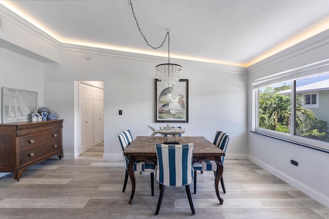 dining room with an inviting chandelier, a tray ceiling, and light hardwood / wood-style flooring