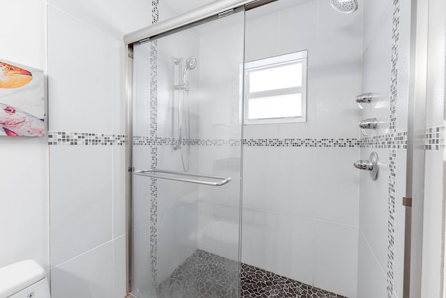 bathroom with a shower with shower door and toilet