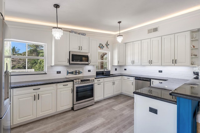 kitchen with white cabinetry, stainless steel appliances, sink, and hanging light fixtures