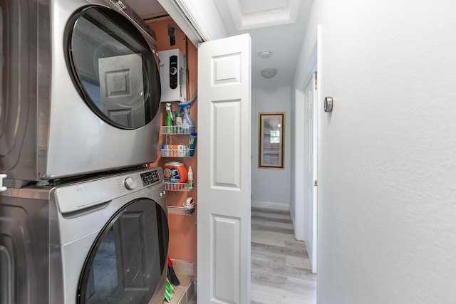 washroom with stacked washer and dryer and light hardwood / wood-style flooring