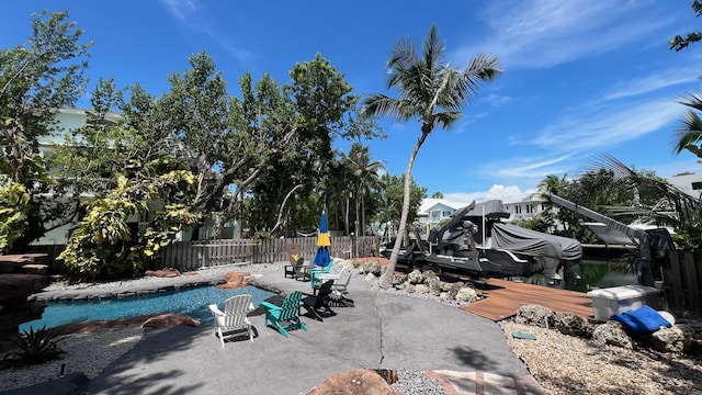 view of swimming pool featuring boat lift, a patio, fence, and a boat dock