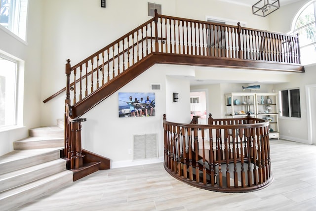 stairway featuring visible vents and a towering ceiling