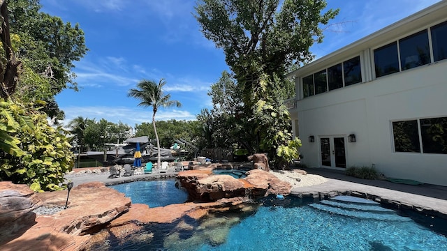 pool with a jacuzzi, a patio area, french doors, and fence