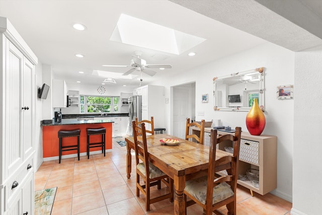 dining room with a skylight, light tile patterned floors, recessed lighting, ceiling fan, and baseboards