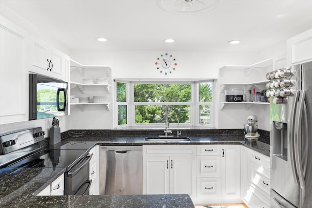 kitchen featuring stainless steel appliances, dark stone counters, a sink, and open shelves