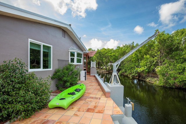 view of side of home with a water view, a patio area, and stucco siding