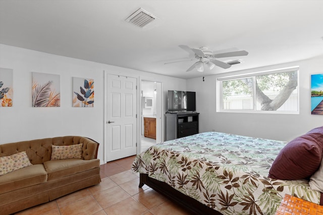 bedroom featuring ceiling fan, light tile patterned flooring, visible vents, and ensuite bathroom