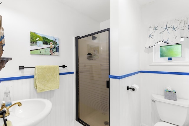 full bath with a wainscoted wall, a stall shower, a sink, and toilet