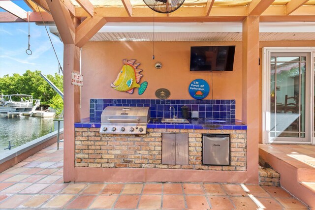 view of patio / terrace featuring area for grilling, a sink, and a water view