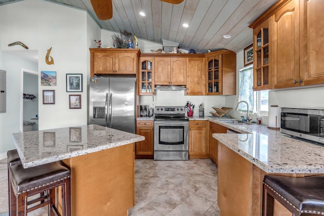 kitchen featuring sink, a breakfast bar area, appliances with stainless steel finishes, light stone counters, and wooden ceiling