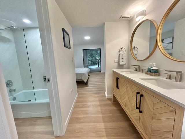 bathroom featuring wood-type flooring, vanity, and shower / bathtub combination