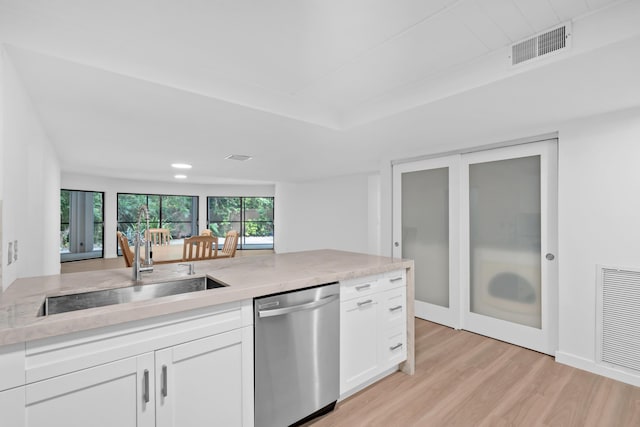 kitchen with dishwasher, sink, white cabinets, light stone countertops, and light hardwood / wood-style flooring