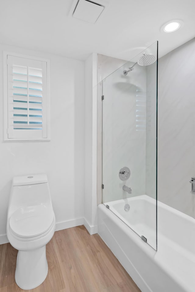 bathroom featuring wood-type flooring, toilet, and tiled shower / bath combo