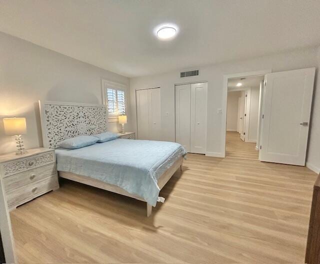 bedroom featuring two closets and light hardwood / wood-style floors