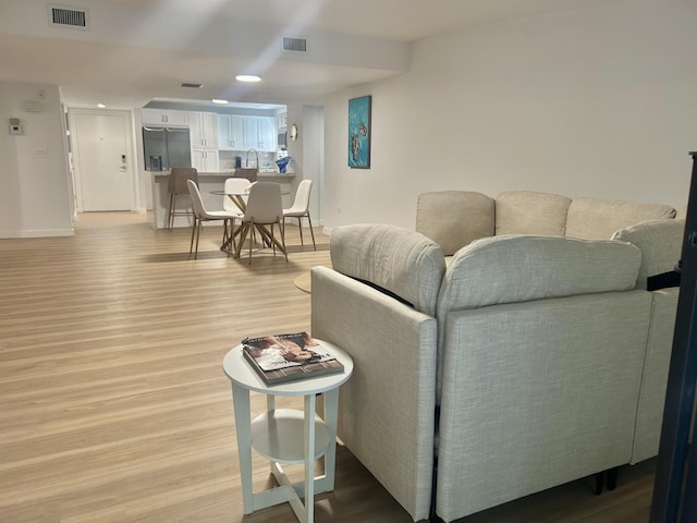 living room featuring sink and light hardwood / wood-style flooring