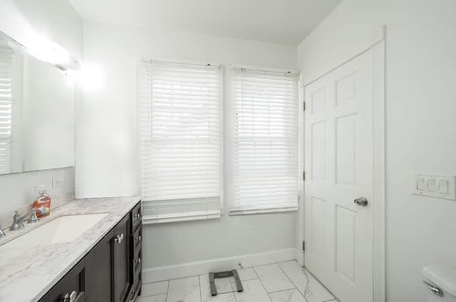 bathroom featuring toilet, marble finish floor, baseboards, and vanity