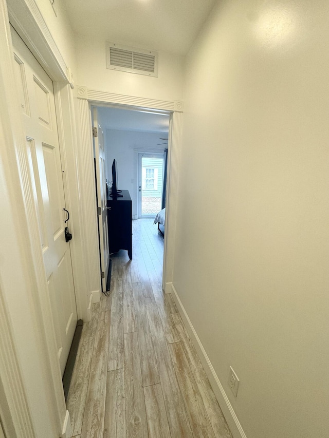 corridor featuring baseboards, visible vents, and light wood-style floors