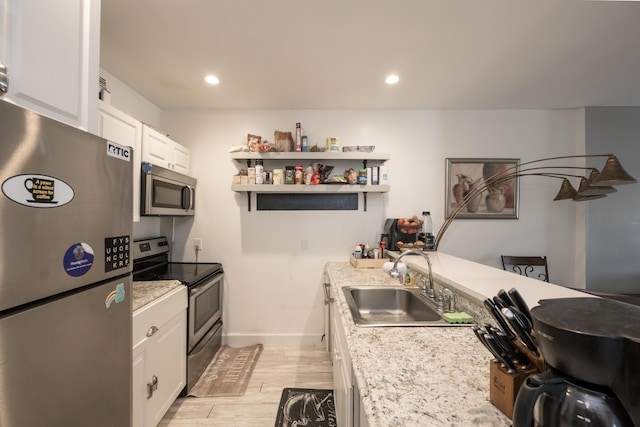 kitchen featuring light wood-style flooring, appliances with stainless steel finishes, white cabinetry, open shelves, and a sink