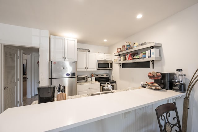 kitchen featuring recessed lighting, stainless steel appliances, a peninsula, white cabinetry, and light countertops