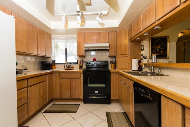 kitchen featuring sink, decorative backsplash, tile counters, light tile patterned floors, and black appliances