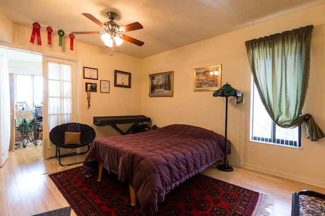 bedroom with multiple windows, ceiling fan, and light hardwood / wood-style floors