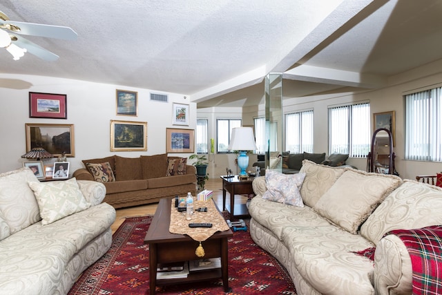 living room featuring wood-type flooring, plenty of natural light, beamed ceiling, and a textured ceiling