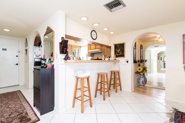 kitchen featuring a breakfast bar, kitchen peninsula, and light tile patterned floors