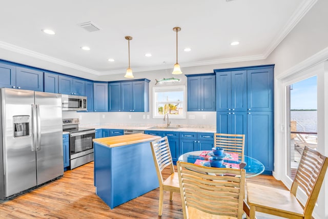 1777 Pine Channel Dr, Little Torch, FL 33042 - kitchen featuring appliances with stainless steel finishes, blue cabinetry, crown molding, light wood-type flooring, and pendant lighting