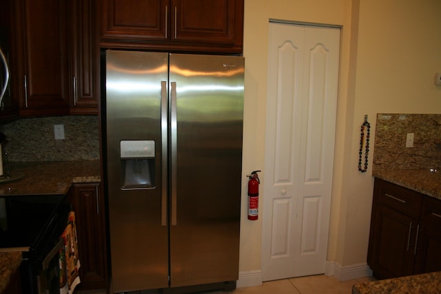 kitchen featuring stainless steel refrigerator with ice dispenser, stone countertops, electric range oven, light tile patterned floors, and decorative backsplash