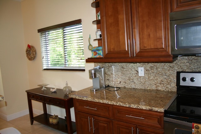 kitchen featuring light stone countertops, decorative backsplash, stainless steel appliances, and light tile patterned floors