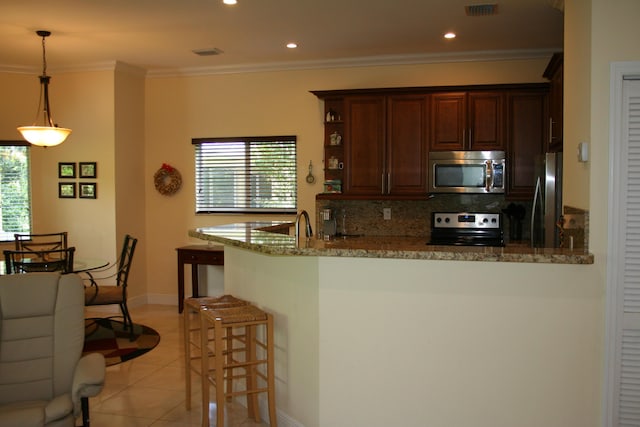 kitchen with a breakfast bar, stone countertops, hanging light fixtures, appliances with stainless steel finishes, and kitchen peninsula