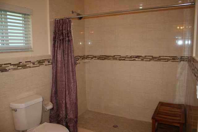 bathroom with a shower with curtain, toilet, and tile walls