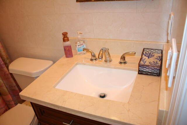 bathroom with tile walls, vanity, and toilet