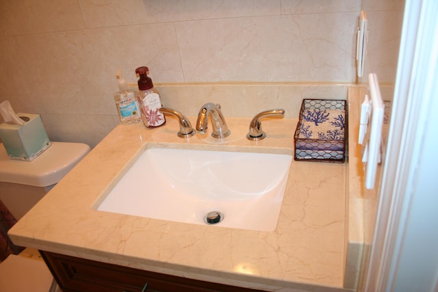 bathroom with sink, tile walls, and toilet