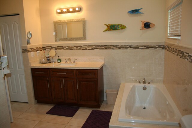 bathroom with vanity, tile patterned flooring, tile walls, and tiled tub