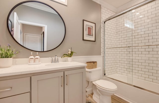 full bathroom featuring vanity, bath / shower combo with glass door, ornamental molding, and toilet