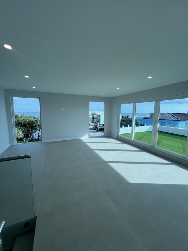 unfurnished living room featuring concrete flooring, a water view, and a healthy amount of sunlight