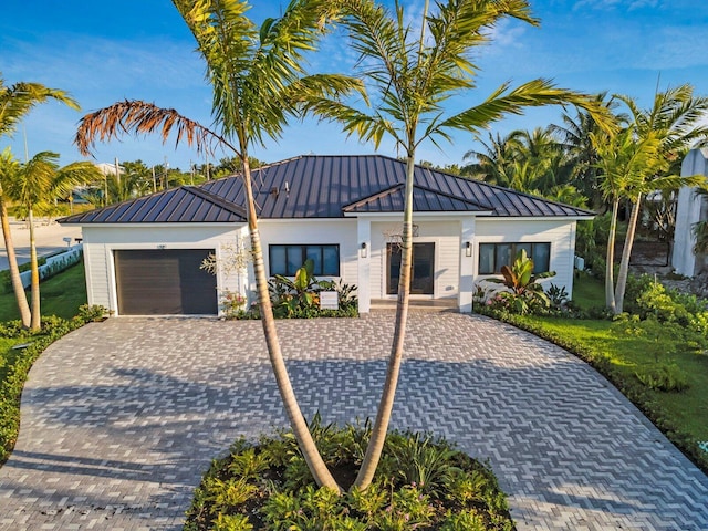 view of front of house with a front lawn, a standing seam roof, metal roof, an attached garage, and driveway