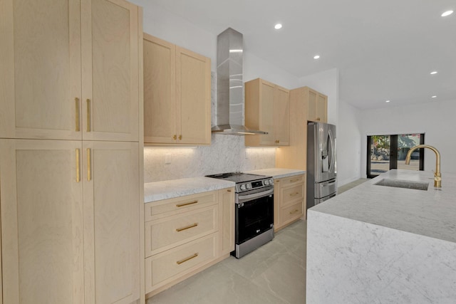 kitchen featuring wall chimney range hood, backsplash, appliances with stainless steel finishes, a sink, and light brown cabinets