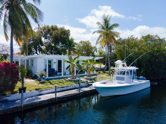 view of dock with a yard, a water view, and a pergola