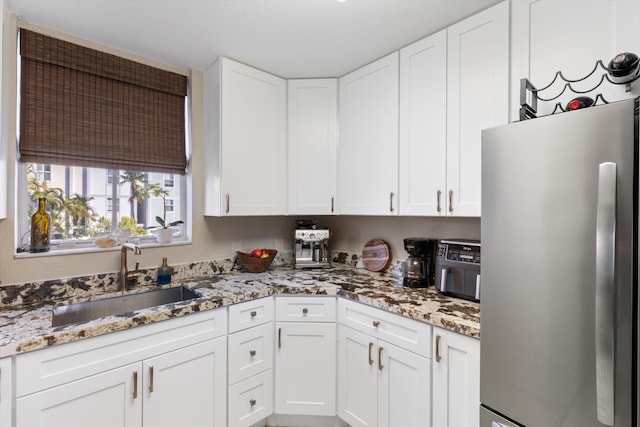 64 Seaside N Ct, Key West, FL 33040 - kitchen featuring freestanding refrigerator, a sink, white cabinets, and light stone counters